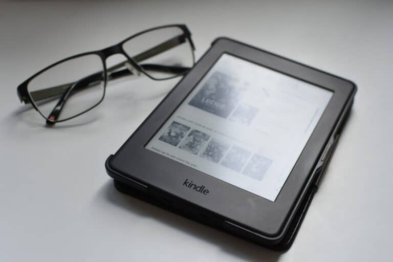 kindle lying on white table with eye glasses